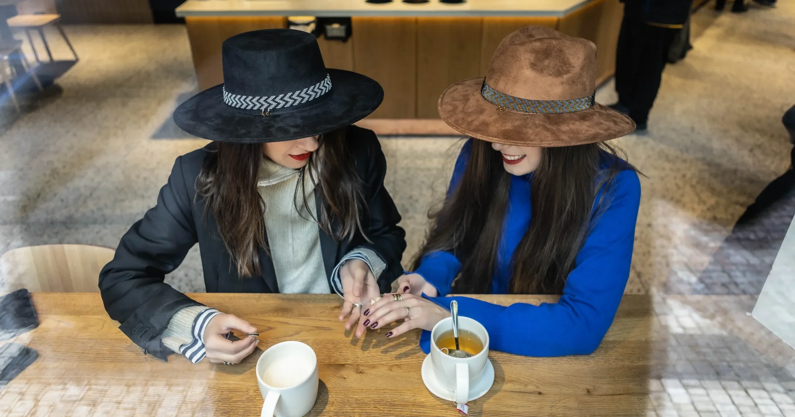 two girls wearing hats in a coffee shop